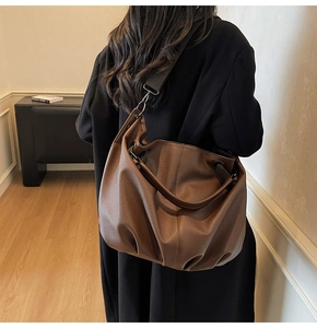 Gros plan du sac en cuir grainé marron avec détails plissés et large bandoulière confort