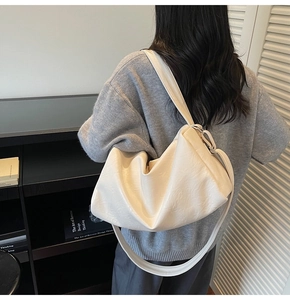 Detail shot of a cream white oversized crossbody bag with soft pleated PU leather texture
