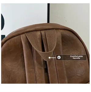 Detail of a brown leather backpack with reinforced stitching and nylon carry handle