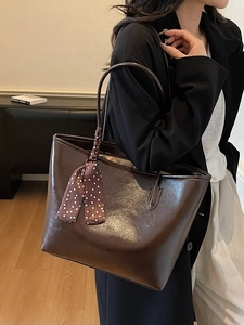 Dark brown patent leather tote bag with polka dot scarf detail shown in a home setting