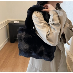 Gros plan sur la texture du sac cabas en peluche noire porté avec un trench-coat