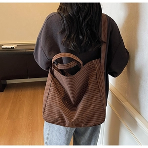Detailed back view of a large brown checkered canvas tote bag worn over the shoulder