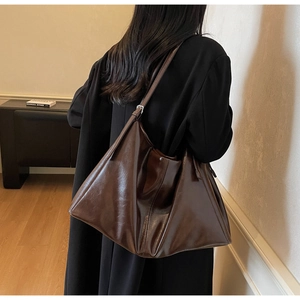 Detailed view of the dark brown glossy leather tote bag showing texture and adjustable strap
