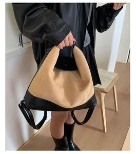 Detail of a dual-color leather tote bag showing mixed textures of suede and leather