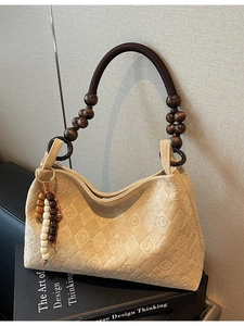 Beige matte vintage tote bag with wood bead handles and embossed diamond pattern