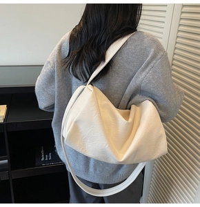 Detailed back view of a large cream white slouchy tote bag worn on shoulder by model