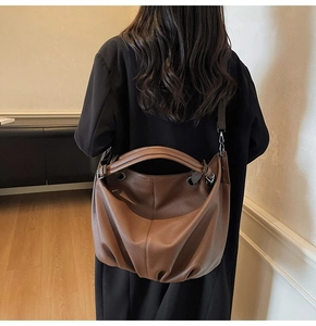 Sac fourre-tout marron en cuir grainé moderne porté par un mannequin en costume noir