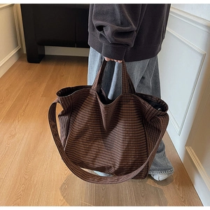 Close-up of brown and black plaid canvas tote bag with adjustable shoulder strap