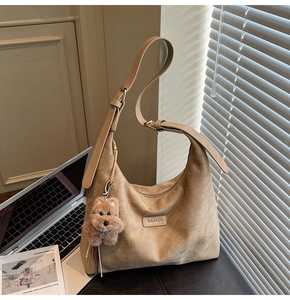 Detail of beige suede tote bag showing brand tag and adjustable shoulder strap
