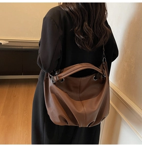 Dettaglio macro della borsa tote in pelle marrone che mostra texture morbida e pieghe