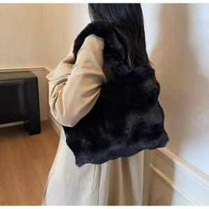Vue détaillée d'un sac cabas en fausse fourrure noire porté avec un trench-coat beige