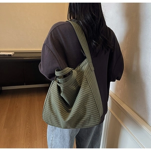 Rear view of model wearing a large green checkered canvas tote bag in a cozy setting