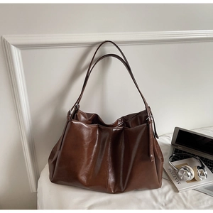 Detail of dark brown tote bag with glossy oily leather texture and double shoulder straps