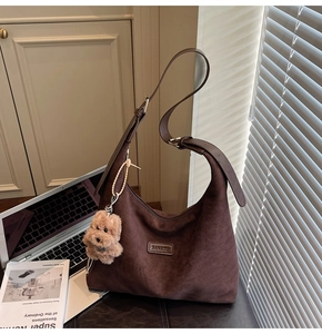 Detail of dark brown suede hobo bag with adjustable strap and plush bear charm