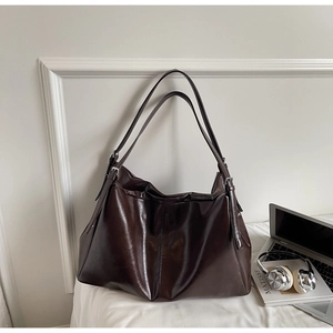 Detail of glossy chocolate brown leather tote bag with silver adjustable buckles and straps