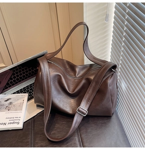 Macro shot of dark brown polished leather tote bag with stylish pleated texture