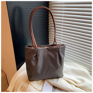 Detail of grey pleated tote bag with thin brown strap and top zipper closure