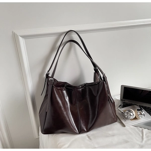 Detail of a dark brown glossy PU leather tote bag with silver metallic adjustment buckles