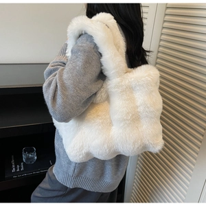 Gros plan sur la texture en fausse fourrure blanche et la large bandoulière de ce cabas