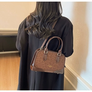 Detailed view of the leopard print crossbody bag featuring gold lettering and leather handles