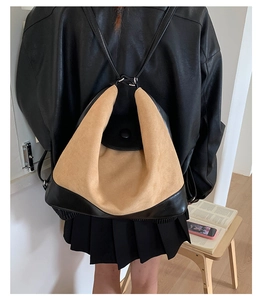 Detail of two-tone brown suede and black leather bag showing the texture and back-worn style