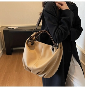 Vue détaillée d'un sac cabas en cuir beige avec anses marron sur un mannequin femme