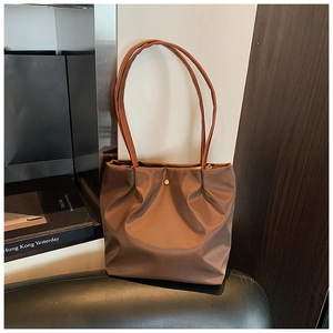 Detail of a brown pleated tote bag featuring a metallic finish and a gold buckle accent