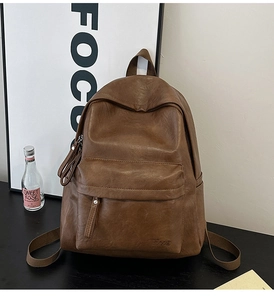 Detail view of the vintage brown faux leather backpack with zippered pocket and embossed logo