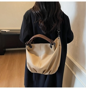 Vue arrière d'un mannequin portant un grand sac hobo beige avec une poignée ronde brune