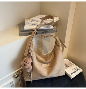 Close-up of brown suede tote bag featuring a leather logo patch and a plush puppy charm