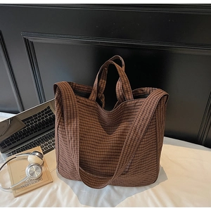 Detailed close-up of brown checkered tote bag showing heavy canvas texture and strap hooks