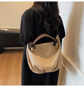 Dettaglio della borsa tote beige minimalista con trama in pelle martellata e gancio in metallo