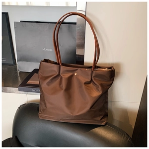 Detailed close-up of dark brown nylon tote bag with zipper and golden button closure