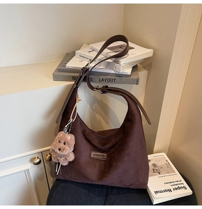 Detail of dark brown suede hobo bag with adjustable strap and cute plush bear charm