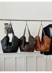 Detailed view of three leather tote bags in black, dark brown, and caramel colors
