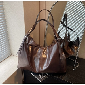 Detail of dark brown glossy tote bag showing the textured pleats and adjustable metal buckle