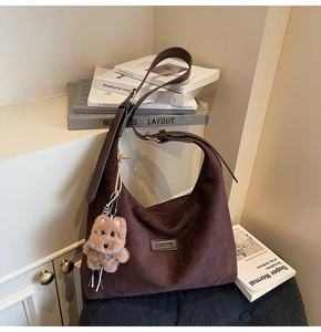 Close-up of brown suede tote bag with BANATU logo and cute plush puppy charm