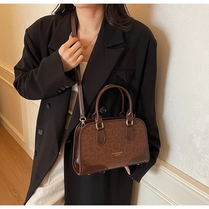 Detail showing vintage leopard print texture and leather branding on a crossbody bag