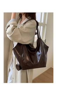 Detailed shot of dark brown glossy leather texture on a large capacity tote bag