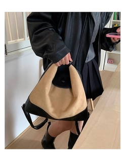 Detail of vintage beige suede tote bag with black leather trim and top handle in lifestyle setting