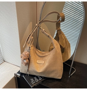 Detail of suede tote bag with BANATU leather logo and a brown teddy bear pendant
