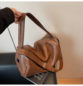 Close-up of soft brown PU leather tote bag with silver zipper and wide strap detail