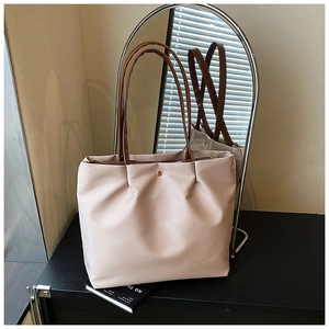 Macro detail of the beige tote bag featuring pleated faux leather and a metal zipper