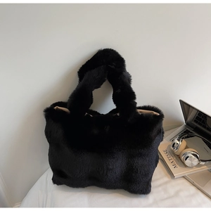 Détail du cabas en fausse fourrure noire avec poignées larges et texture pelucheuse
