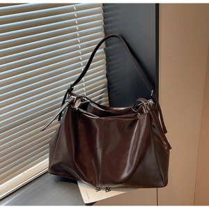 Detail of dark brown leather tote bag with adjustable metal buckle and smooth glossy finish