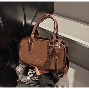 Detailed view of brown boston bag featuring mixed suede and leather texture with gold lettering