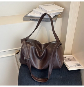 Macro shot of dark brown leather tote bag showing soft texture and metal buckle detail