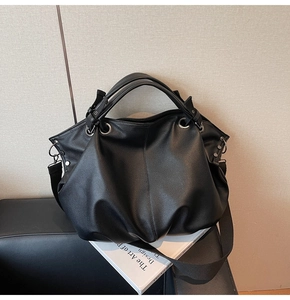 Détail du cabas en cuir grainé noir avec anneaux argentés et large bandoulière tissée
