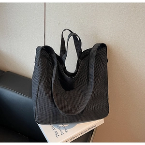 Detailed view of black checkered canvas tote bag placed on books in a stylish setting