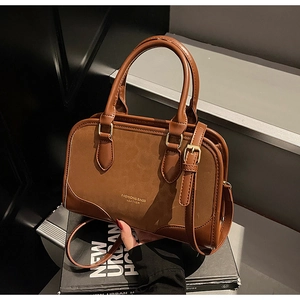 Detail of vintage brown leather handbag featuring mixed textures and golden hardware accents